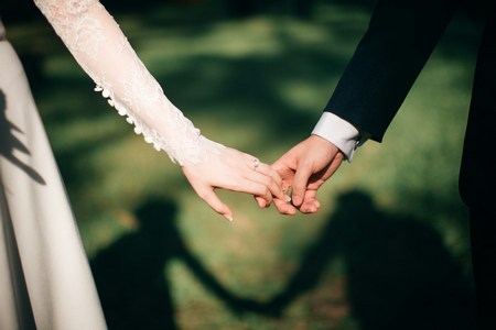 A woman and man holding hands on their wedding day