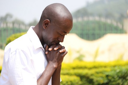 Man praying with hands folded outdoors