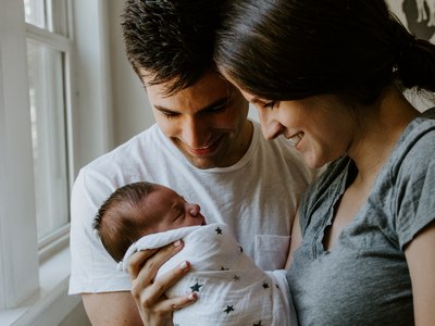 Young parents holding their baby near a window and smiling