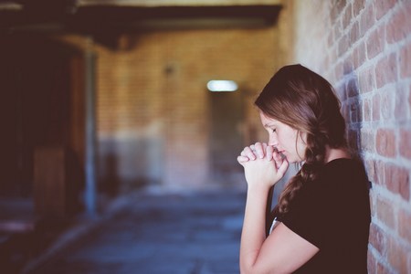 Girl praying behind a building