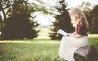A woman sitting outdoors in the sunshine reading the Bible