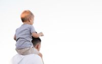 A toddler sitting on his father's shoulders