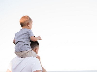 A toddler sitting on his father's shoulders