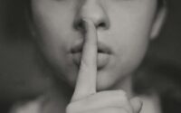 A girl with her finger up to her lips for someone to be quiet. Shhh.