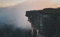 View of a cliff from on high with mist in the background.