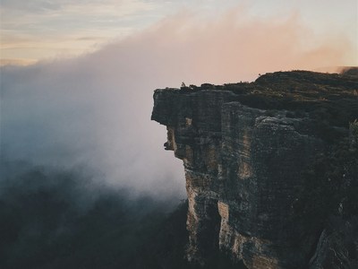 View of a cliff from on high with mist in the background.