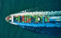 A cargo ship full of containers leaving a wake in the ocean.