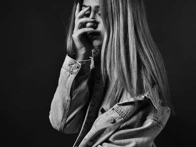 A girl with her hands hiding her face like she is ashamed.