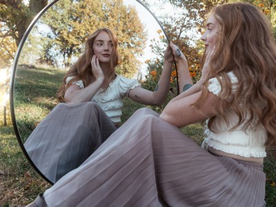 A girl looking in a mirror that she is holding up