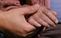 A person holding an elderly person's hand and offering help.