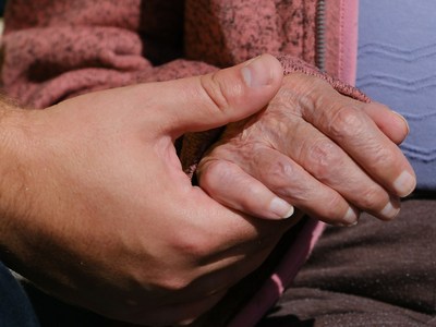 A person holding an elderly person's hand and offering help.