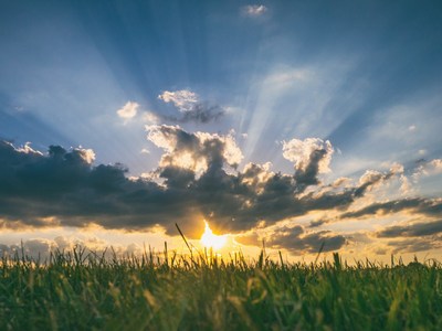 The sunset or sunrise between clouds and a field of grass